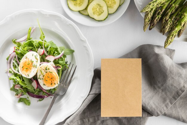 Vista superior deliciosa ensalada en un plato blanco con tarjeta vacía