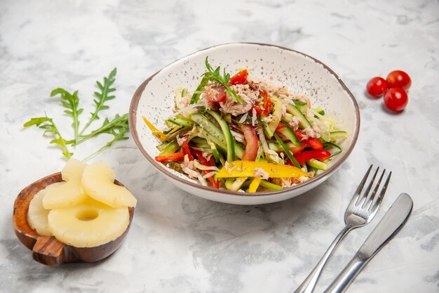 Vista superior de la deliciosa ensalada de pollo con verduras, tomates, piñas secas, cubiertos en superficie blanca manchada