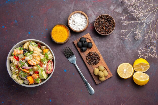 Vista superior deliciosa ensalada de verduras con condimentos y rodajas de limón sobre fondo oscuro dieta de comida de ensalada de salud