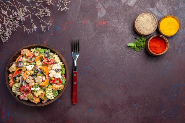 Vista superior deliciosa ensalada de verduras con diferentes condimentos sobre fondo oscuro ensalada de almuerzo de dieta vegetal de salud