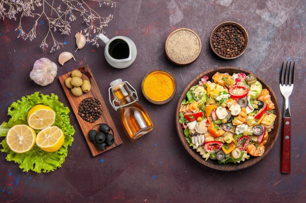 Vista superior deliciosa ensalada de verduras con tomates en rodajas, aceitunas y champiñones sobre fondo oscuro ensalada de comida dieta saludable