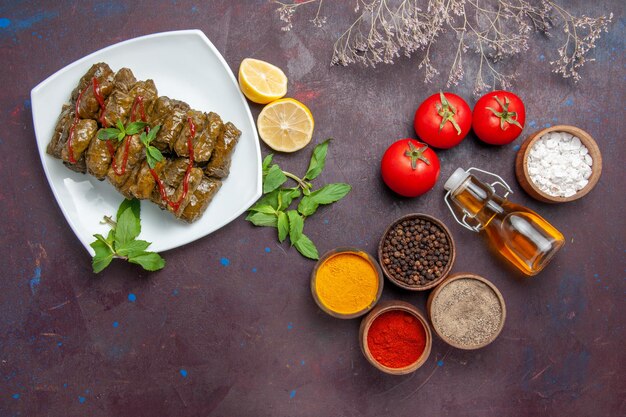 Vista superior de la deliciosa hoja dolma con condimentos de limón y tomates en el fondo oscuro plato hoja comida carne cena