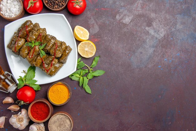 Vista superior de la deliciosa hoja dolma con condimentos y tomates en el fondo oscuro plato hoja comida carne cena