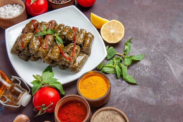 Vista superior de la deliciosa hoja dolma con condimentos y tomates sobre fondo oscuro plato de carne hoja comida cena