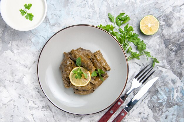 Vista superior de la deliciosa hoja dolma con verdes sobre superficie blanca