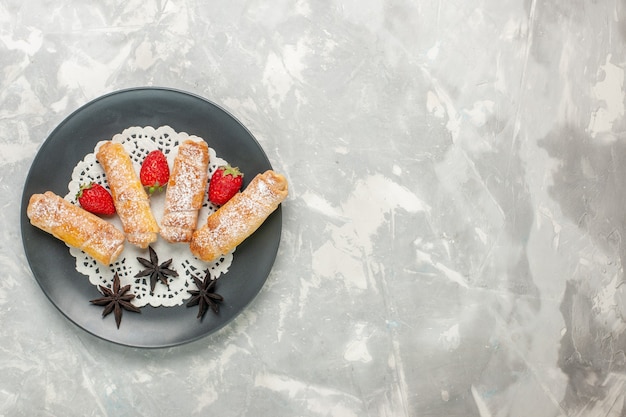 Vista superior de la deliciosa masa de bagels de azúcar en polvo con fresas sobre superficie blanca