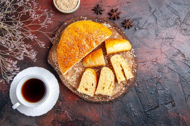 Vista superior deliciosa pastelería dulce cortada en trozos con té sobre una superficie oscura