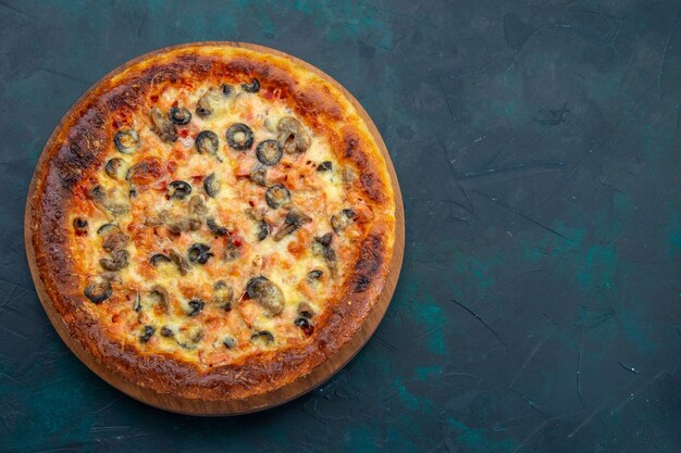 Vista superior de la deliciosa pizza cocida con queso y aceitunas en el escritorio azul oscuro
