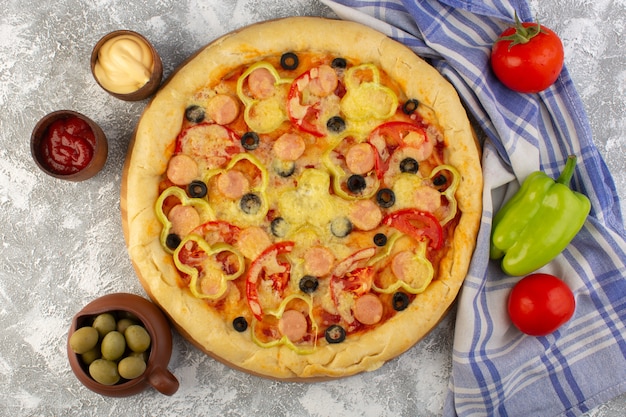 Vista superior deliciosa pizza con queso con aceitunas, salchichas y tomates en el fondo brillante comida de comida de masa italiana de comida rápida