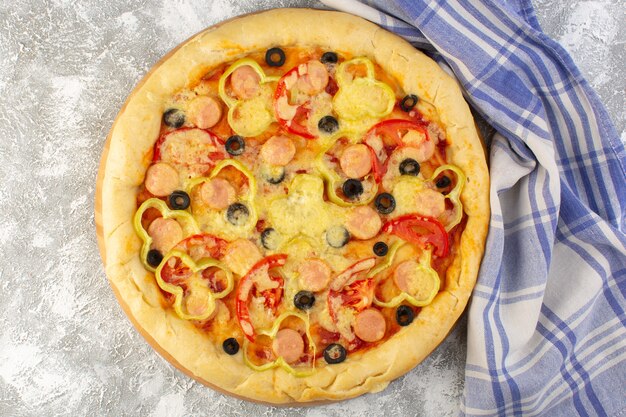 Vista superior deliciosa pizza con queso con aceitunas, salchichas y tomates en el fondo gris comida de masa italiana de comida rápida