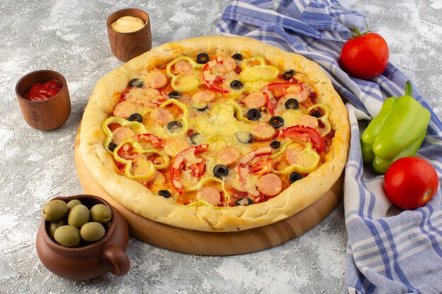 Vista superior deliciosa pizza con queso con aceitunas, salchichas y tomates en el fondo gris comida rápida masa comida comida