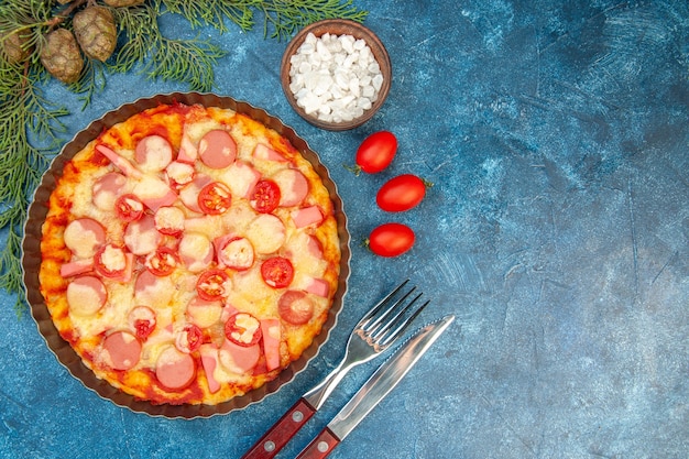 Vista superior deliciosa pizza de queso con salchichas y tomates en el fondo azul pastel de masa de alimentos foto en color comida rápida italiana