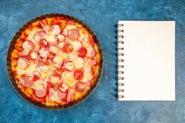 Vista superior de una deliciosa pizza de queso con salchichas y tomates sobre fondo azul, ensalada, comida, pastel, fotografía en color, comida rápida