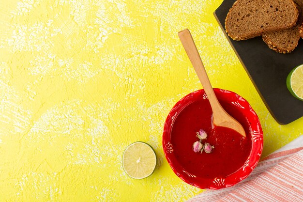 Vista superior deliciosa salsa de tomate con pan de limón y pan en la mesa amarilla sopa comida comida vegetal