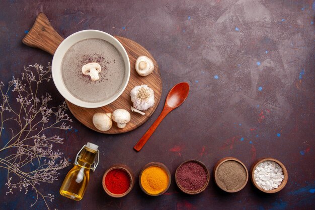 Vista superior deliciosa sopa de champiñones con champiñones frescos y condimentos en el escritorio oscuro