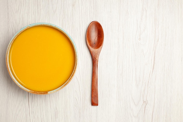 Vista superior deliciosa sopa de crema sopa de color amarillo en el plato de cena de crema de comida de salsa de sopa de escritorio de madera blanca