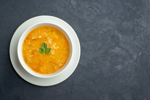 Vista superior deliciosa sopa dentro de un plato blanco sobre una superficie oscura