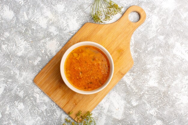 Vista superior de la deliciosa sopa dentro del plato sobre la superficie de luz gris