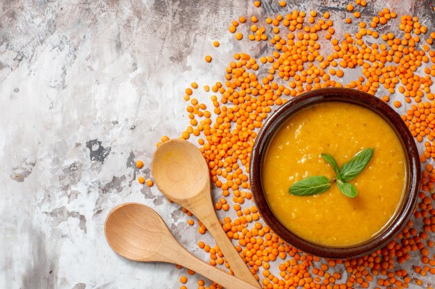 Vista superior deliciosa sopa de lentejas con lentejas crudas sobre fondo claro sopa de plantas foto en color plato de semillas de alimentos