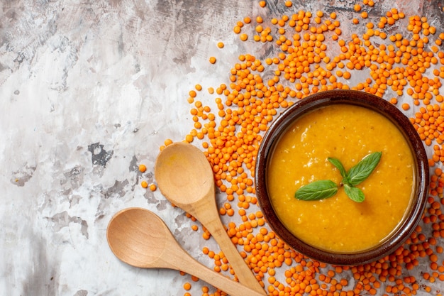 Vista superior deliciosa sopa de lentejas con lentejas crudas sobre fondo claro sopa de plantas foto en color plato de semillas de alimentos