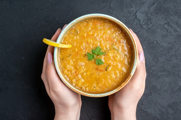 Vista superior deliciosa sopa de lentejas con placa de sujeción femenina panes de pan oscuro sobre superficie oscura