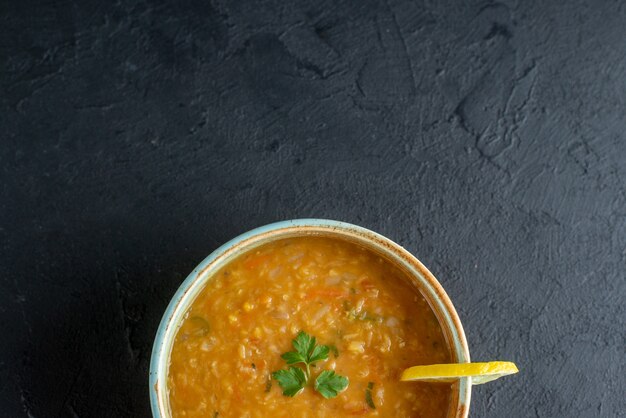 Vista superior deliciosa sopa de lentejas con una rodaja de limón dentro de la placa sobre una superficie oscura