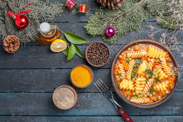 Vista superior de la deliciosa sopa de pasta de pasta italiana en espiral con condimentos en el escritorio azul oscuro cena cocina plato de sopa de pasta de color