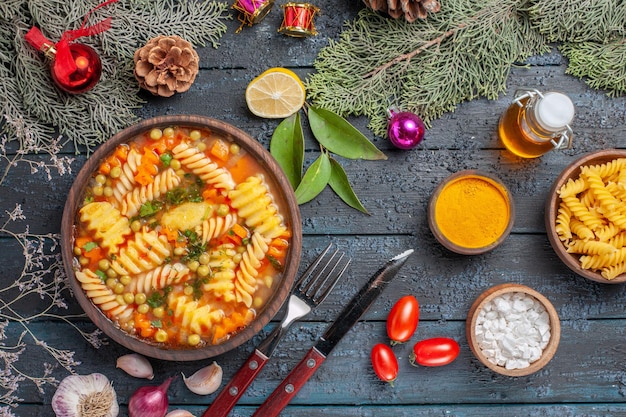 Vista superior de la deliciosa sopa de pasta de pasta italiana en espiral en el plato de color de pasta de sopa de cocina de escritorio rústico azul oscuro