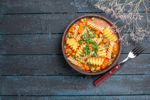 Vista superior deliciosa sopa de pasta de pasta italiana en espiral con verduras en el escritorio azul oscuro plato de cena salsa de sopa de pasta italiana