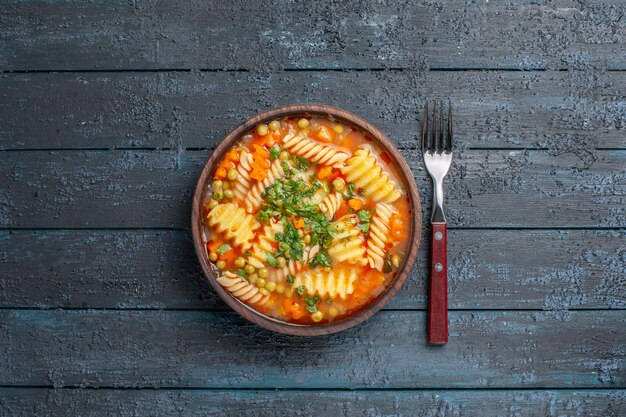 Vista superior deliciosa sopa de pasta de pasta italiana en espiral con verduras en el escritorio oscuro plato de cena salsa de sopa de pasta italiana