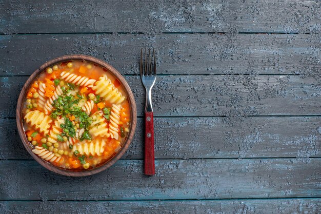 Vista superior deliciosa sopa de pasta de pasta italiana en espiral con verduras en el oscuro escritorio rústico plato de cena salsa de sopa de pasta italiana