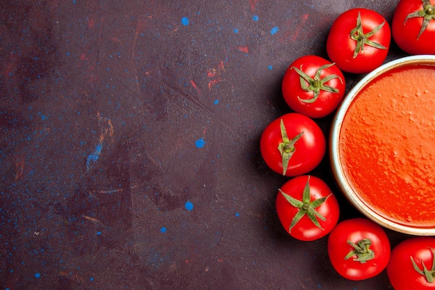 Foto gratuita vista superior deliciosa sopa de tomate en un círculo con tomates rojos frescos en la salsa de plato de comida de sopa de tomate de fondo oscuro