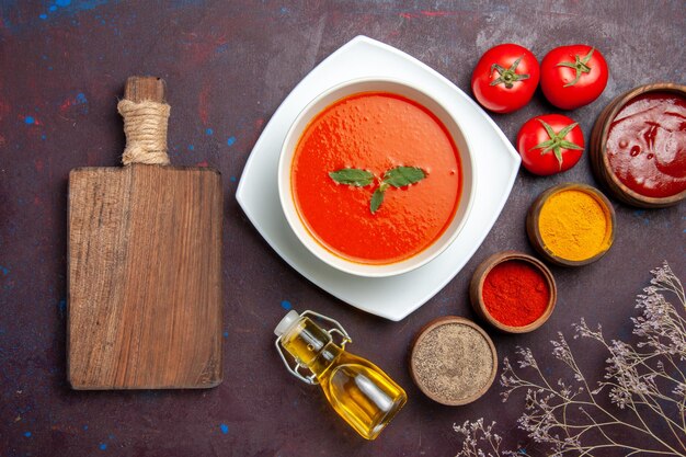 Vista superior deliciosa sopa de tomate con diferentes condimentos sobre fondo oscuro plato salsa tomate color comida sopa