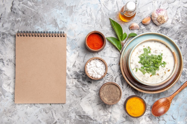 Vista superior deliciosa sopa de yogur dovga con condimentos en un plato de piso blanco, sopa de leche, lácteos