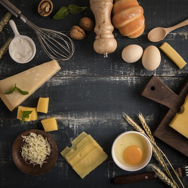 Vista superior de una deliciosa tabla de quesos con nueces, huevos y harina en una mesa con espacio de copia