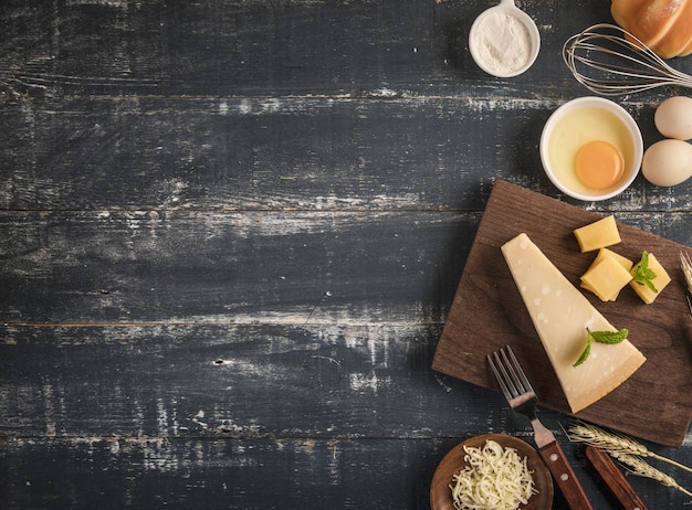 Vista superior de una deliciosa tabla de quesos con nueces, huevos y harina en una mesa con espacio de copia