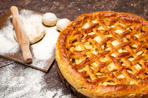 Una vista superior deliciosa tarta de manzana con forma redonda de masa y harina sobre el fondo oscuro pastel galleta azúcar fruta