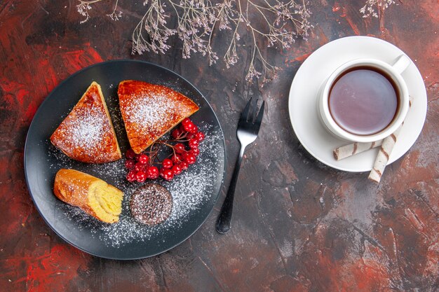 Vista superior deliciosa tarta en rodajas con frutos rojos sobre la mesa oscura pastel dulce té de tarta