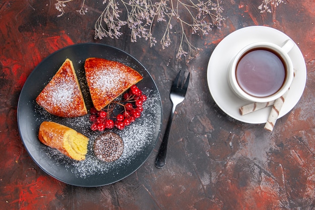 Vista superior deliciosa tarta en rodajas con frutos rojos sobre la mesa oscura pastel dulce té de tarta