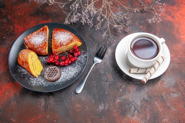 Vista superior deliciosa tarta en rodajas con frutos rojos sobre la mesa oscura pastel dulce té de tarta