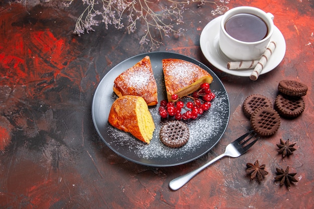 Vista superior deliciosa tarta en rodajas con frutos rojos sobre mesa oscura pastel tartas dulces té