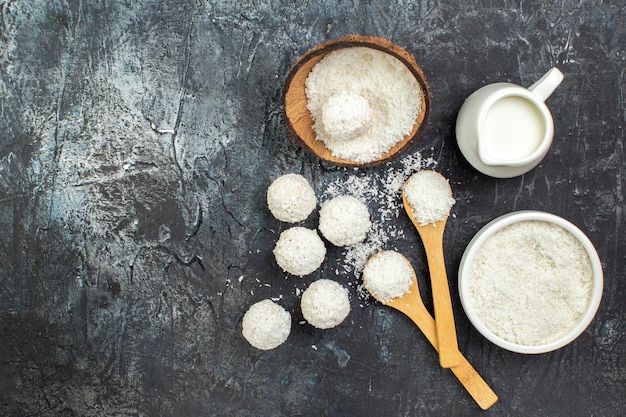 Vista superior deliciosas bolas de coco deliciosos dulces con leche sobre fondo oscuro galleta dulce galleta golosina dulces colores lácteos