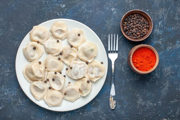 Vista superior de deliciosas bolas de masa hervida dentro de la placa junto con pimienta en la oscuridad, comida de masa comida cena carne calorías