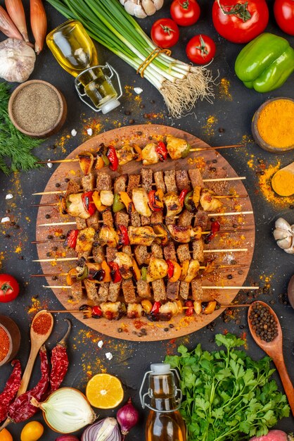 Vista superior deliciosas brochetas de pollo en tablero de madera y otras cosas en la mesa negra