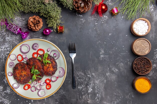 Vista superior deliciosas chuletas con aros de cebolla en la cocina de comida de carne de plato de fondo gris