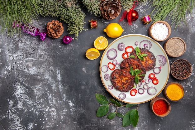 Vista superior deliciosas chuletas con aros de cebolla en el fondo gris plato comida de carne