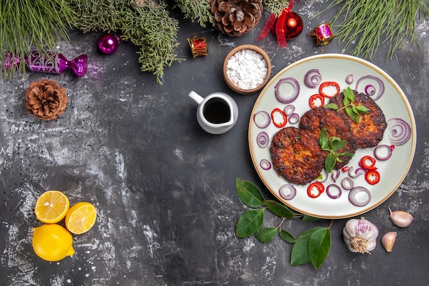 Vista superior deliciosas chuletas con aros de cebolla en el fondo gris plato comida foto carne