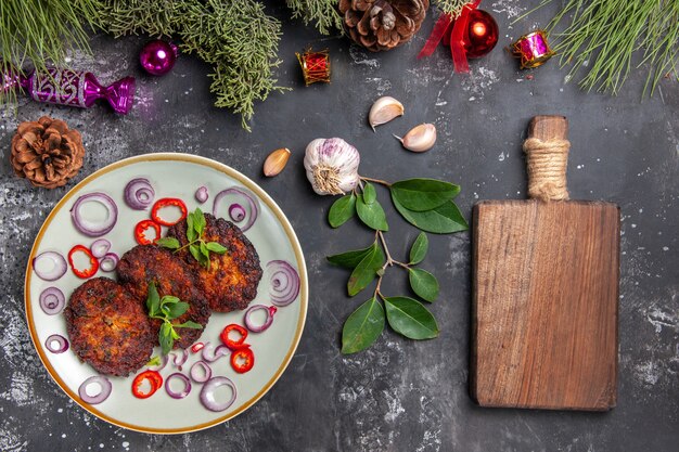 Vista superior deliciosas chuletas con aros de cebolla en piso gris comida foto plato carne