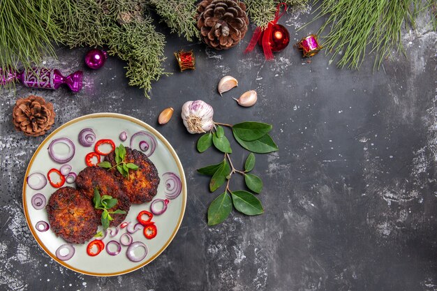 Vista superior deliciosas chuletas con aros de cebolla sobre fondo gris comida foto plato carne