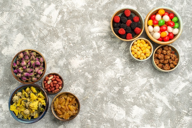 Vista superior deliciosas confituras con dulces, flores secas y nueces sobre fondo blanco, galleta de azúcar de nueces dulces